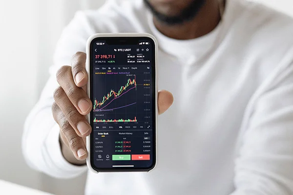 Image of man holding phone with financial app displayed on it